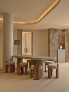 Large, well-lit room with a marble floor, a dining table, and multiple chairs, creating a comfortable and inviting atmosphere
