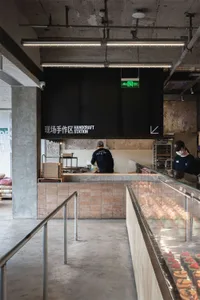 A modern restaurant with a brick wall, black and white color scheme, and a man working behind the counter in a well-lit space