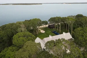 A modern house with a white exterior and black roof, surrounded by a pool and trees, with natural sunlight and a serene atmosphere