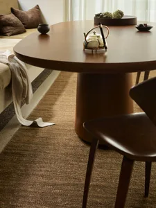 Cozy modern living space with a wooden dining table, chairs, couch, and wooden floor, lit by dim lighting