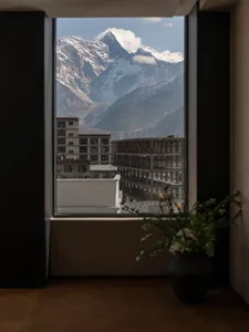 A serene living area with a large window offering a stunning mountain view, natural light, and a potted plant
