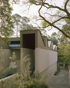 A modern house with a gray exterior, large window, and natural surroundings, featuring a minimalist and functional design with natural materials and simple lines, under soft and diffused lighting