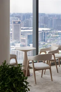 A modern dining space with a glass wall offering a city view, a dining table, and comfortable seating