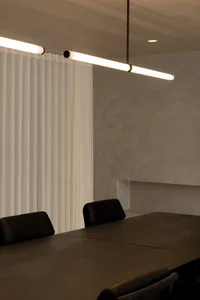 A dimly lit dining area with a wooden table and two black chairs, surrounded by a modern space with clean lines and minimalistic design elements