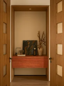 Bathroom with a wooden cabinet, red top, picture, vase, sink, and potted plant, well-lit with natural and artificial light