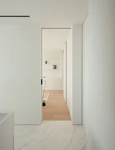 A bright and inviting kitchen with a wooden floor, a white door, and a refrigerator visible through the open door