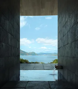 A serene spa or bathroom with a large pool, stone walls, and a stunning ocean view through a large window