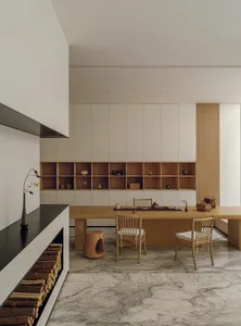 Warm and inviting kitchen with wooden floors, white walls, a wooden dining table, and a fireplace, lit by natural sunlight