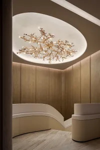 Dimly lit lobby with a wooden ceiling, a large chandelier, and a staircase in the background