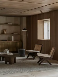 Cozy living space with wooden floors and walls, a couch, chair, and dining table, dim lighting, and a warm atmosphere