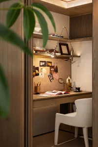 A cluttered study with a desk, chair, and couch, featuring a potted plant and a cozy atmosphere