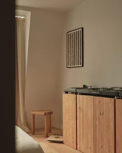 Cozy bedroom with a wooden floor, a wooden cabinet, and a wooden chair, featuring a bed in the corner and a turntable near the cabinet