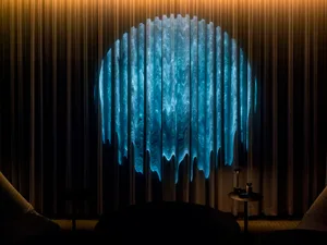 Dimly lit room with a blue patterned curtain, a chair, and a dining table in the background