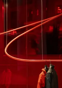 A dimly lit red bedroom with a bed and a hanging orange dress, creating a warm and cozy atmosphere