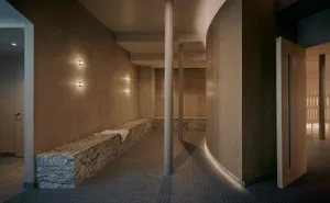 Bathroom with stone-tiled floor, stone bench, and stone wall in a modern space with dim lighting