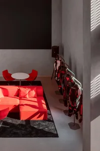 A modern living room with a red couch, a dining table, and a blackboard on the wall, set in a well-lit space with a warm atmosphere
