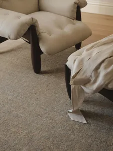 Cozy living room with a brown carpet, two chairs, and a couch, featuring dim lighting and a warm atmosphere
