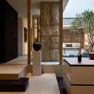 A well-lit kitchen or living area with a marble counter, stone wall, and a dining table near a large window