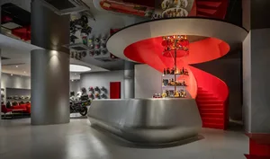 A modern bar with a silver circular bar surrounded by bottles in various shapes and sizes, creating a stylish atmosphere