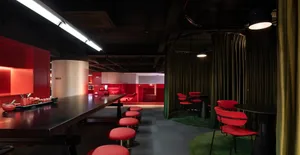 Cozy modern restaurant with a long bar, red accents, and dim lighting, encouraging social interaction