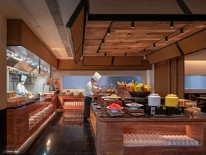 A busy kitchen with a chef preparing food in front of a wooden counter with various fruits and bowls of food on it