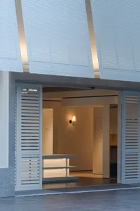 A modern kitchen dining space with a white color scheme, dim lighting, and a dining table and chairs