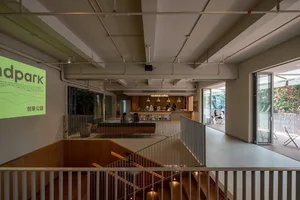 A large, open space with a staircase, balcony, and comfortable seating areas, featuring wood and metal materials and well-distributed lighting