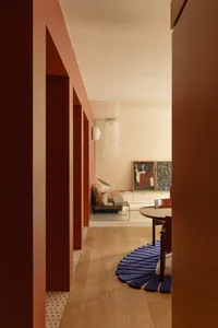 Warm and inviting room with a wooden floor, red walls, a dining table, couch, and lamp, creating a comfortable space for relaxation and socializing