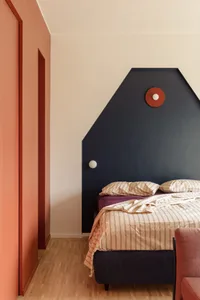 Cozy bedroom with a bed, chair, and red accent wall, suggesting a comfortable and inviting space