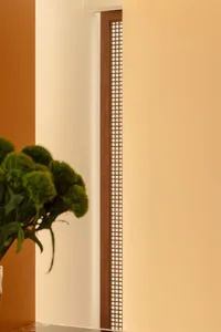 A modern room with a patterned wooden wall, a vase with flowers on a table, and a warm and inviting atmosphere