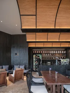 A casual bar scene with a wooden counter, cups, bottles, and a vase, set in a social atmosphere