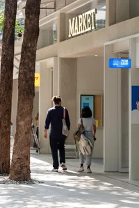 一對情侶在建築物前的行人道上漫步的悠閒都市場景，以建築物與行人道為主要視覺元素