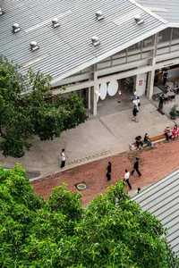 市場前一條磚石步道，人們朝各個方向走動，手提包包，在熱鬧繁華的戶外場景中