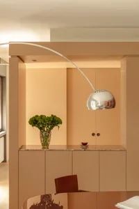 A modern kitchen with a marble countertop, a potted plant, and natural light from a window