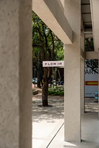 前景有樹木的城市街景，兩旁排列著建築物與停車，捕捉人們與車輛的日常景象