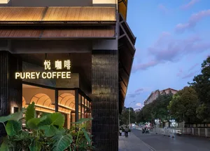 A modern coffee shop with a black and white color scheme, featuring a large window, comfortable furniture, and a well-lit atmosphere