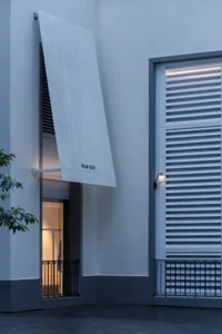 Photograph of a commercial building with a white concrete facade, a large window, and a white awning, taken in dim lighting