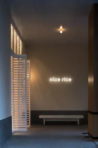 燈光明亮的餐區，靠牆擺放木製長椅，配有發光招牌，周圍有餐桌及溫馨氛圍