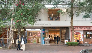 A modern bookstore with a brick floor, wooden furniture, and natural light from windows, creating a warm and inviting atmosphere for customers to browse and read