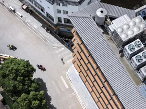 寧靜的街景，背景有建築，周圍環繞樹木，左側停放一台機車，場景中有兩個人