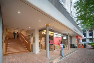 現代磚牆立面建築，配有玻璃門與木質階梯，自然光線灑落其中