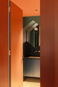 Bathroom with a blue cabinet, black countertop, and a mirror mounted above the sink, set against a dimly lit background