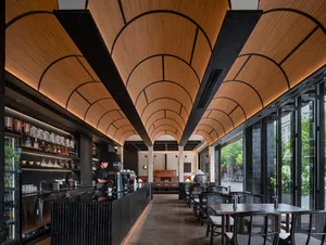 Cozy restaurant with dim lighting, wooden furniture, and metal accents, featuring a bar and dining area with potted plants and vases