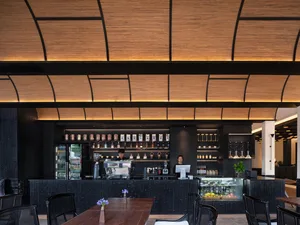 A well-lit restaurant with a wooden floor, a black counter, and a wooden table with chairs, set against a warm and inviting background