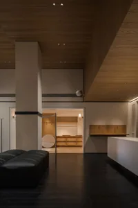 A well-lit living room with a wooden floor, a couch, a chair, and a dining table, creating a comfortable and inviting atmosphere