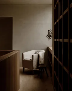 A cozy living space with a wooden floor, a white chair, and a potted plant adding a touch of greenery