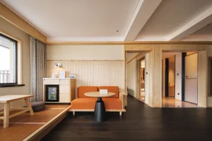 Cozy modern living space with wooden floors, a wooden table, and soft warm lighting, featuring a couch, chair, dining table, and decorative items