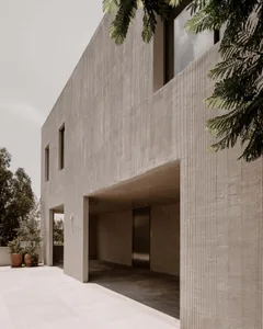 Photograph of a modern building with a concrete exterior, featuring a large window and door, and a sleek contemporary design