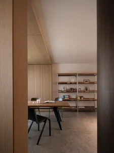 Dimly lit study with a wooden table, chairs, and bookshelves, surrounded by books and a cozy atmosphere