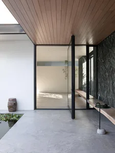 Modern house with a large glass door and a bench outside, featuring a clean and sleek design with a focus on open spaces and natural light